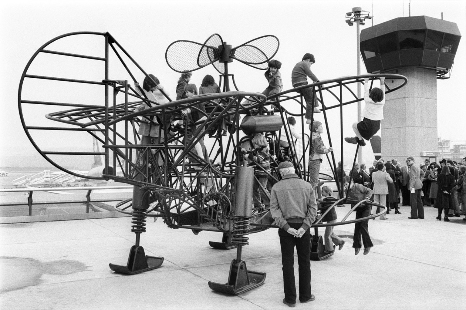 Children climbing the iron sculpture &quot;Wolkenhuepfer 1977&quot; by Swiss artist Berhard Luginbuehl on the spectators&#039; terrace of terminal B at the airport in Kloten near Zurich, Switzerland,  ...