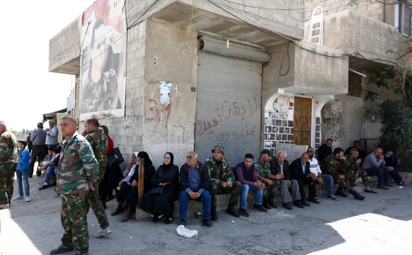 epa06643568 Soldiers stand near relatives of people allegedly detained by Jaysh al-Islam fighters as they wait during evacuation of fighters and civilians from Douma, in east Damascus, Syria, 03 April ...