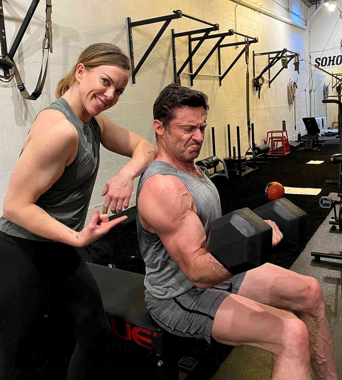Hugh Jackman avec sa coach, soulevant une haltère.
