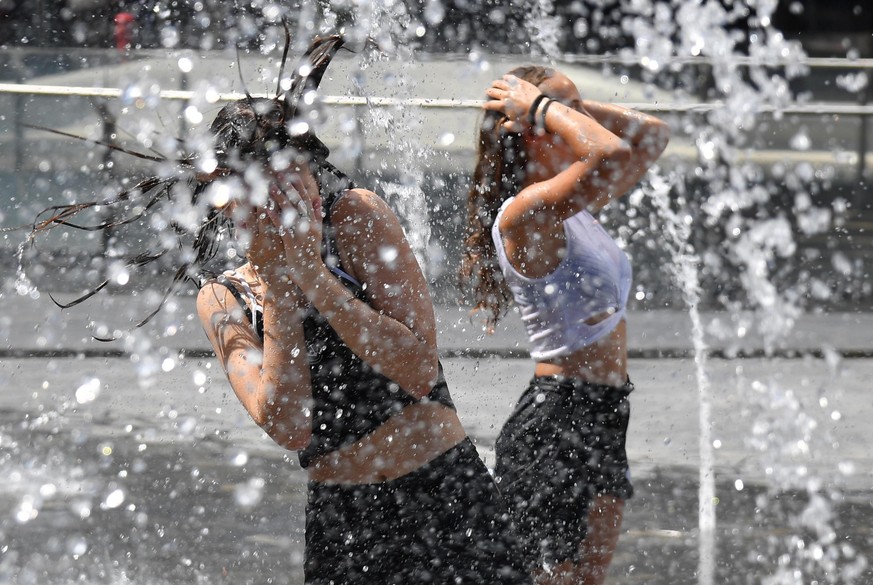 epa07677578 Girls cool off as water sprinkles from a fountain in cetral Gai Aulenti square, in Milan, Italy, 27 June 2019. Temperatures registered 36 degrees Celsius in Milan with hot winds and high h ...
