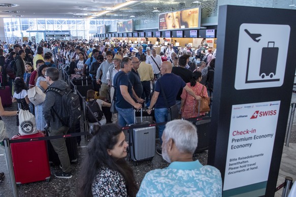 epa10747427 People line up in long queues as they wait in front of the check-in counters to be processed on their way to their holiday destinations, at the airport in Zurich, Switzerland, 15 July 2023 ...