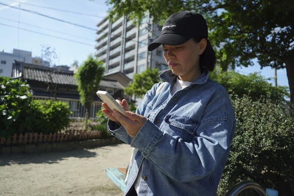 Yang Caiying, who is living in exile in Japan, scrolls through her phone in Nagoya, Japan, Friday, May 17, 2024. (AP Photo/Dake Kang)
China US Digital Cage Photo Essay