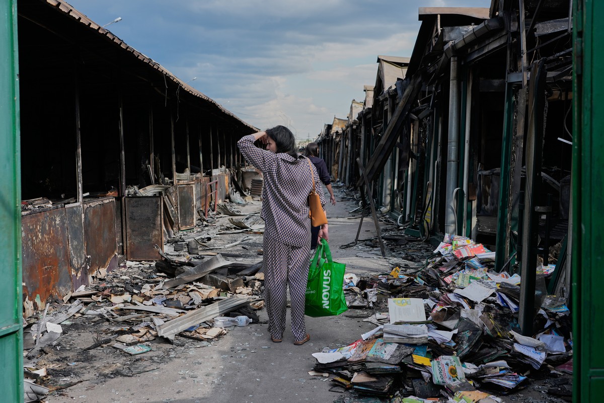 A woman reacts as she looks at charred books after a fire at the country's biggest book market, caused by a recent Russian missile attack, in Kyiv, Ukraine, Wednesday, Aug. 19, 2026. (AP Photo/Ef ...