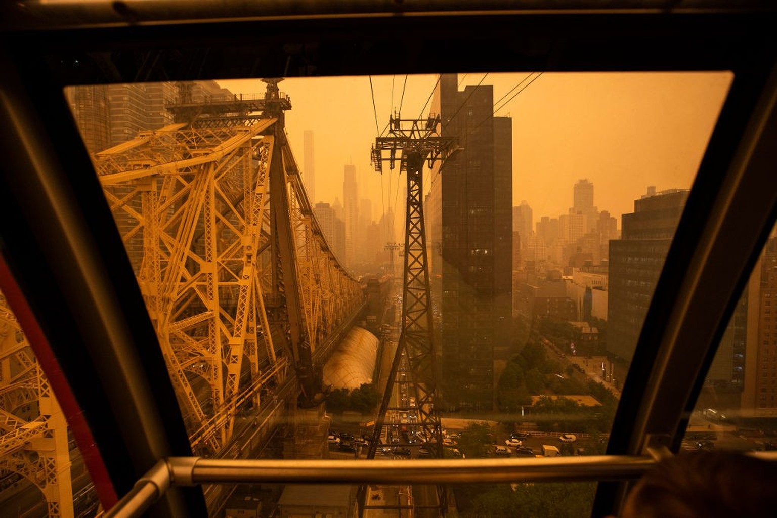 NEW YORK, NEW YORK - JUNE 7: The tramway to Roosevelt Island passes the Ed Koch Queensboro Bridge as smoke from Canadian wildfires casts a haze over the area on June 7, 2023 in New York City. Air poll ...