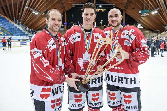 Team Canadas players Andrew Ebbett, Mason Raymond and Maxim Noreau celebrate with the trophy after winnig the final game between Team Canada and Team Suisse at the 91th Spengler Cup ice hockey tournam ...