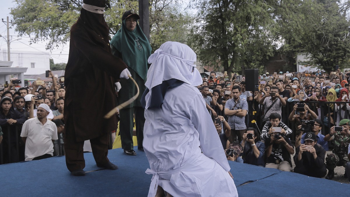 A Shariah law official whips a woman who is convicted of prostitution during a public caning outside a mosque in Banda Aceh, Indonesia, Friday, April 20, 2018. Indonesia's deeply conservative Ace ...