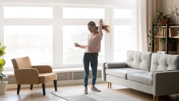 A woman is dancing in her apartment, she is happy and happy