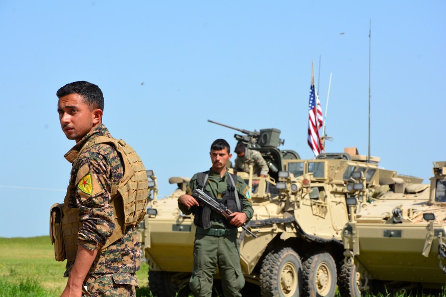 epa05935398 Soldiers of the People&#039;s Protection Units (YPG) Kurdish militia stand guard next to a US eight-wheeled armored fighting vehicles, near al-Ghanamya village, al-Darbasiyah town at the S ...