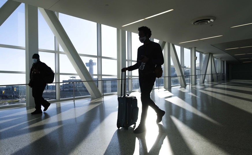 epa08838155 Travelers walk through John F. Kennedy International airport in New York, New York, USA, 23 November 2020. The United States? Centers for Disease Control and Prevention (CDC) has issued a  ...