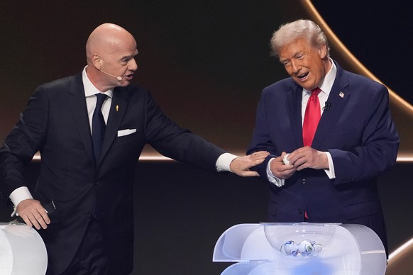 FIFA President Gianni Infantino, left, pauses President Donald Trump, right, during the draw for the 2026 soccer World Cup at the Kennedy Center in Washington, Friday, Dec. 5, 2025. (AP Photo/Evan Vuc ...