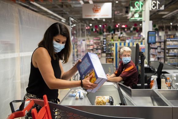 Une personne paie des courses a la caisse a une vendeuse portant un masque sur le visage dans un magasin Migros le mercredi 8 juillet 2020 a Crissier. Les masques sont obligatoires dans les magasins d ...