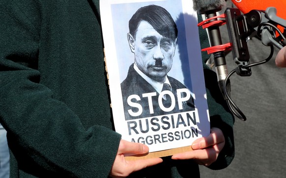 epa09784222 A protester in Sarajevo holds a photograph depicting Russian President Vladimir Putin as Adolf Hitler, during a protest against Russia&#039;s attack on Ukraine, in Sarajevo, Bosnia and Her ...