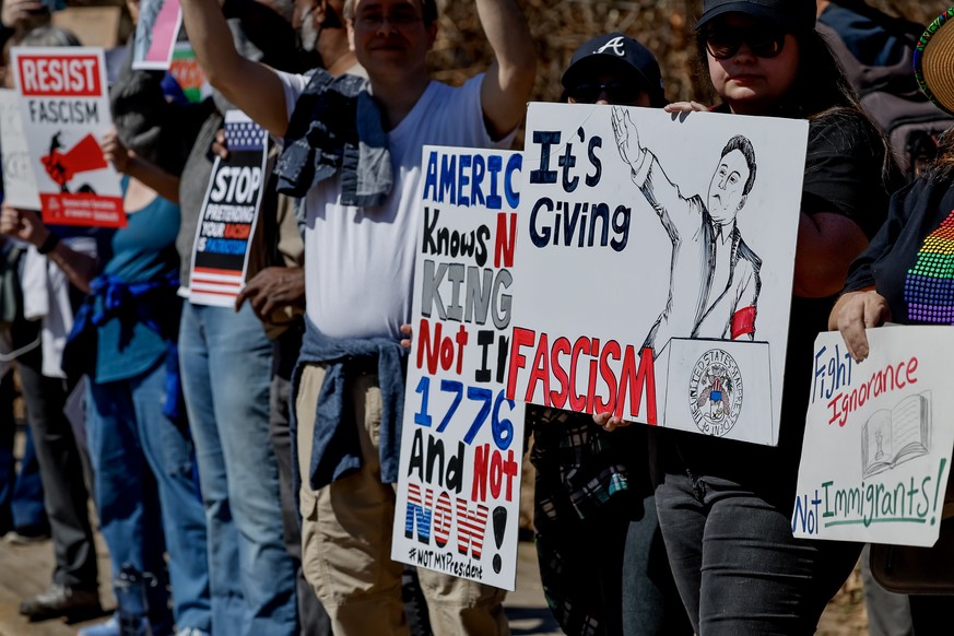 epa11933436 Demonstrators hold placards and flags while participating in a &#039;No Kings&#039; democracy protest against recent Trump administration policies and actions at Piedmont Park in Atlanta,  ...