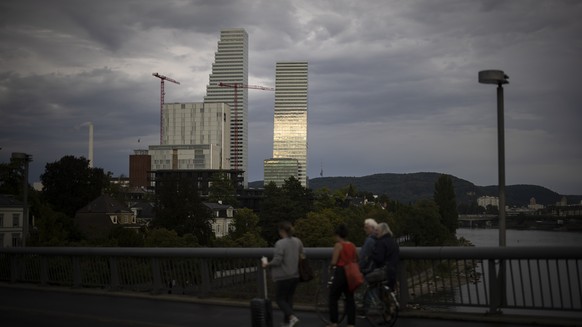 Passanten gehen ueber die Wettsteinbruecke vor dem Roche-Turm Bau 1 und 2, am Freitag, 2. September 2022 in Basel. Der 205 Meter hohe Roche Turm Bau 2 des Schweizer Pharmaunternehmens Roche Holding AG ...
