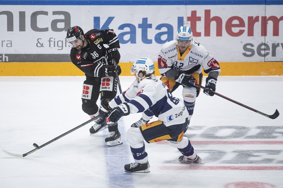 From left, Lugano's player Mark Arcobello and Zug's player Yannick Zehnder, during the preliminary round game of the National League 2022/23 between HC Lugano against EV Zug at the ice stadi ...