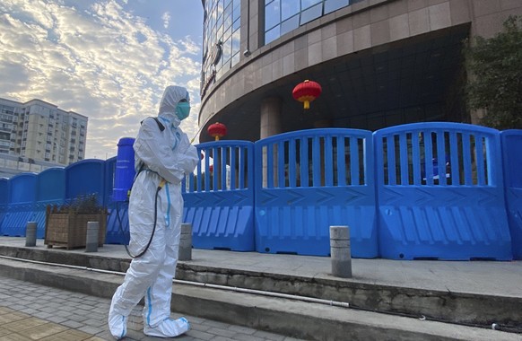 FILE - A worker in protectively overalls and carrying disinfecting equipment walks outside the Wuhan Central Hospital, China on Feb. 6, 2021. Experts drafted by the World Health Organization to help i ...