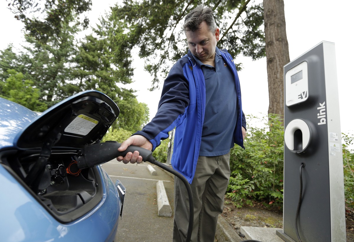 Patrick Conner' shows how to plug his Nissan Leaf electric car at a charging station at the public library in Hillsboro, Ore., Tuesday, May 19, 2015. Fuel-efficient, hybrid and electric cars are  ...