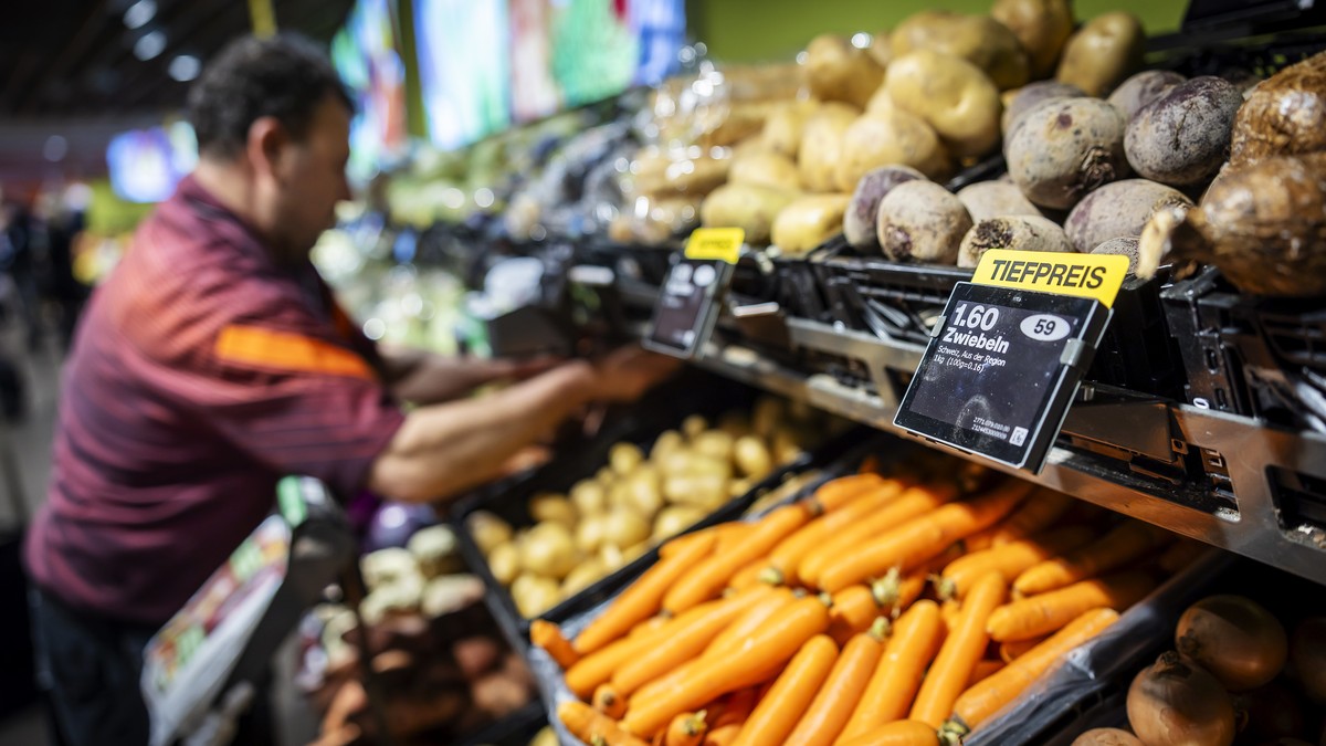 Ein Mitarbeiter raeumt Gemuese ein, neben einem Schild mit der Aufschrift "Tiefpreis" in der Migros Limmatplatz, aufgenommen anlaesslich einer Medienkonferenz zu Neuerungen in den Migros-Sup ...