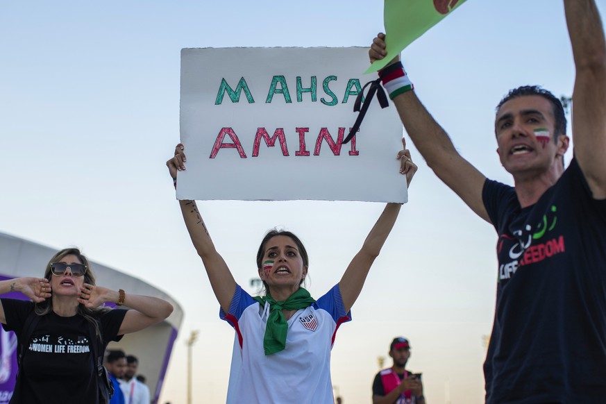 A woman holds up a sign reading Mahsa Amini, a woman who died while in police custody in Iran at the age of 22, during a protest after the World Cup group B soccer match between Wales and Iran, at the ...