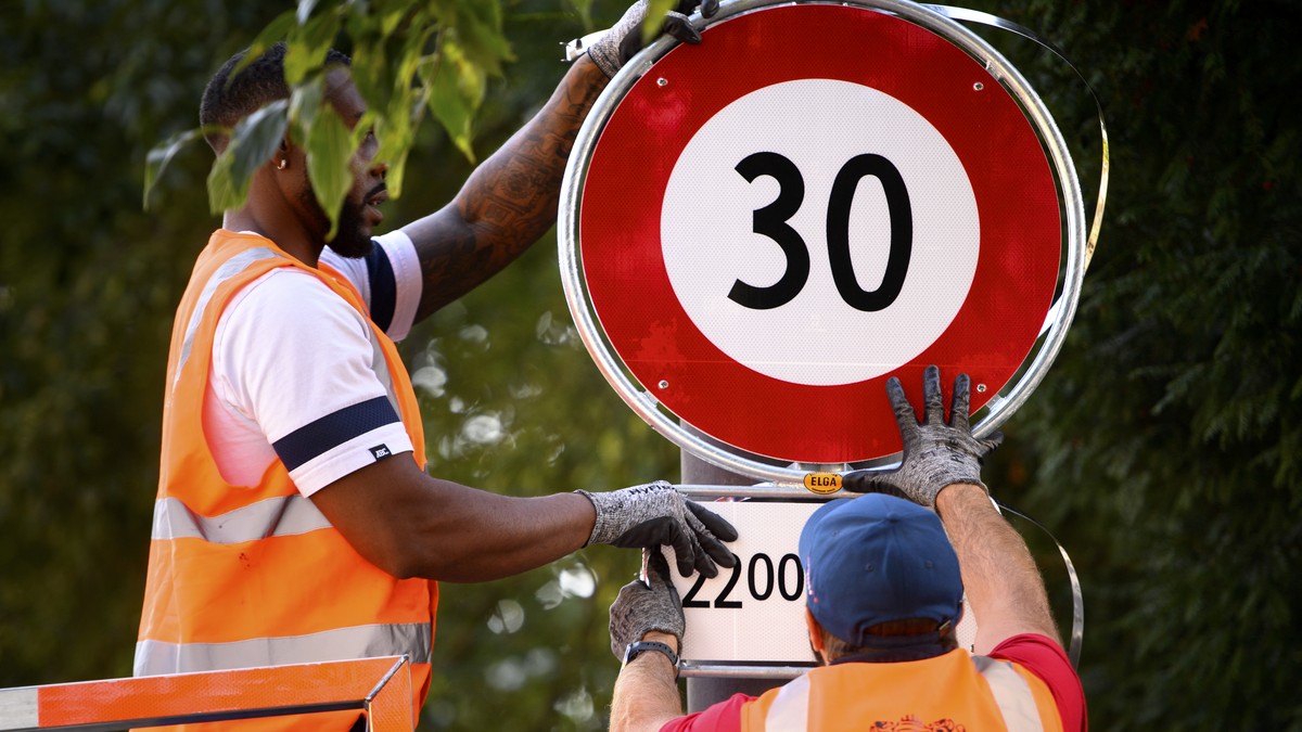 Deux employes de la ville de Lausanne mettent en place un panneau de circulation signalant l'interdiction de rouler a plus de 30km/h, de 22h00 a 06h00, ce lundi 13 septembre 2021 dans une rue de  ...