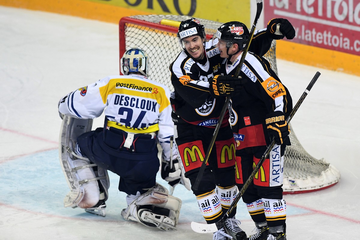 Lugano's Patrik Zackrisson, right, and Dario Buergler, center, celebrate the 4-1 goal against Ambri's goalkeeper Gauthier Descloux, left, during the preliminary round game of National League ...