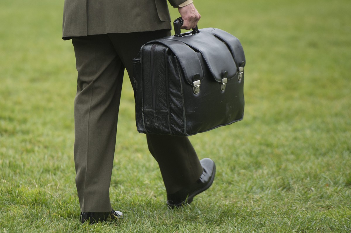 epa05007957 A Major in the US Marine Corps carries a briefcase known as the 'football', which contains materials that could be used by the president to authorize a nuclear attack, while walk ...
