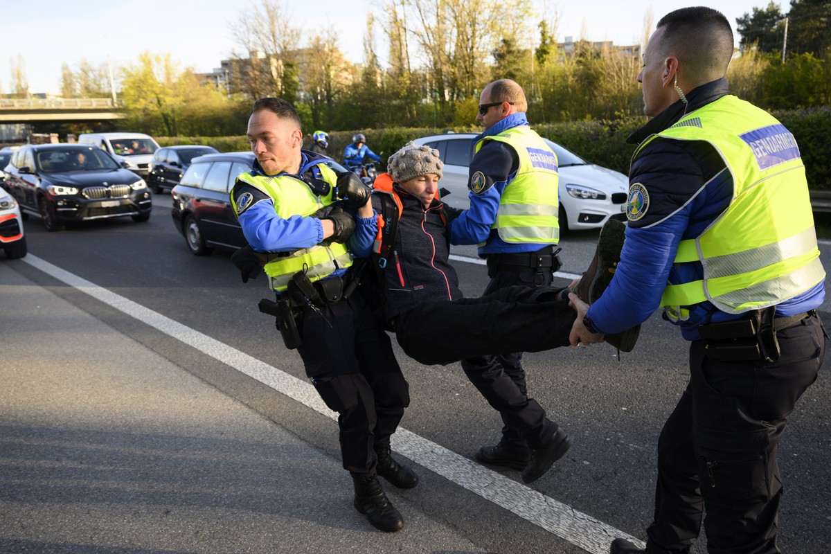epa09884071 Police officers arrest climate activist after they sit down in the road during the 'Renovate Switzerland' a roadblock action, A1a freeway, in Lausanne, Switzerland, 11 April 2022 ...