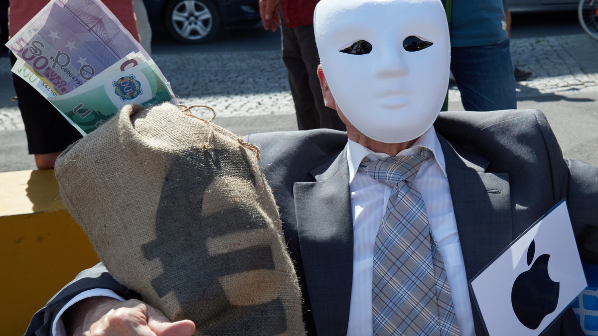epa06760267 An activist from the nonprofit organization Campact representing Apple hugs a mock bag of money during a street performance in front of the Federal Ministry of Finance building in Berlin,  ...