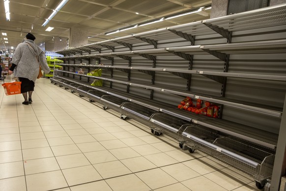 A person walks past the empty product shelves in a supermarket after many people are buying up essential goods due to the fear of the effects due to the coronavirus COVID-19, in Geneva, Switzerland, S ...