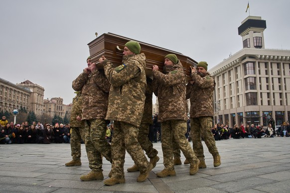People kneel down as Ukrainian servicemen carry the coffin of their fellow-soldier and a well-known documentary photographer Kostiantyn Huzenko, 28, who was killed in Russia-Ukraine war, during the fu ...