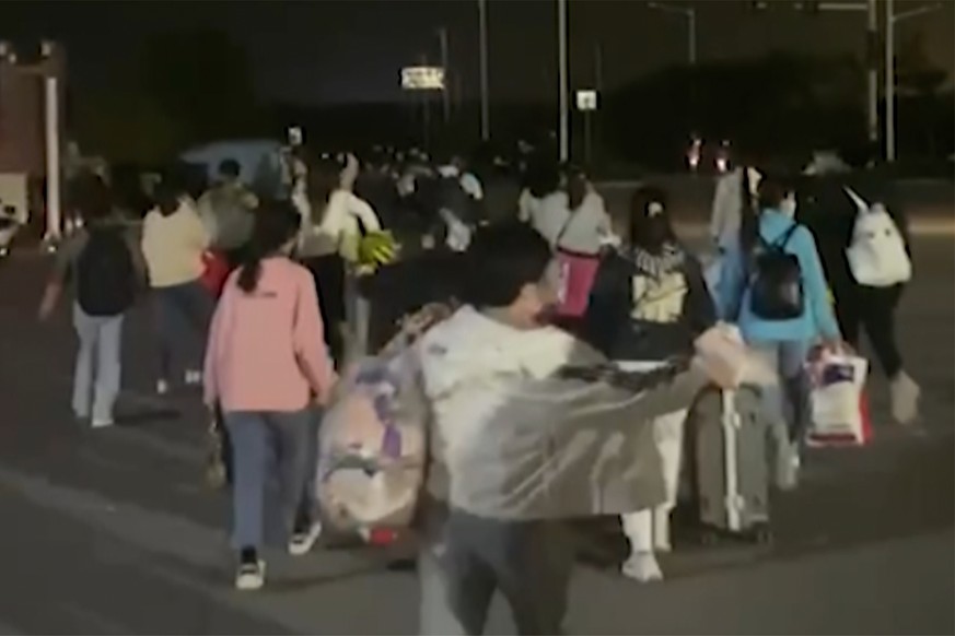 In this photo taken from video footage and released by Hangpai Xingyang, people with suitcases and bags are seen leaving from a Foxconn compound in Zhengzhou in central China's Henan Province on Satur ...