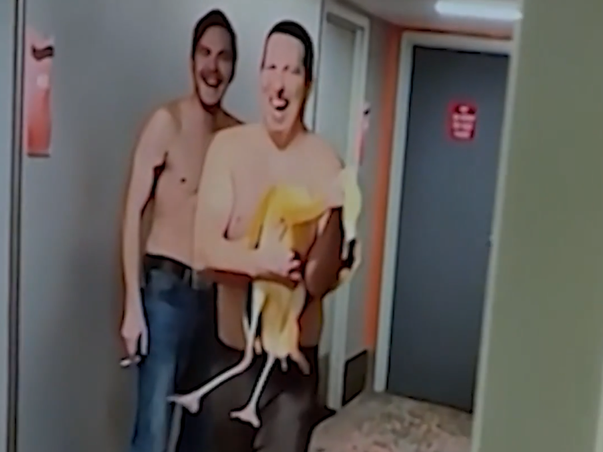 Der Mann trägt den Flamingo durch den Flur seines Hotels.