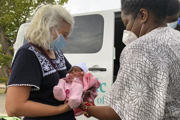 Guerline Jozef, with the Haitian Bridge Alliance, right, hands aid worker Tiffany Burrow six-day-old Grace Francesca Xavier outside the Val Verde Humanitarian Border Coalition in Del Rio, Texas on Sat ...