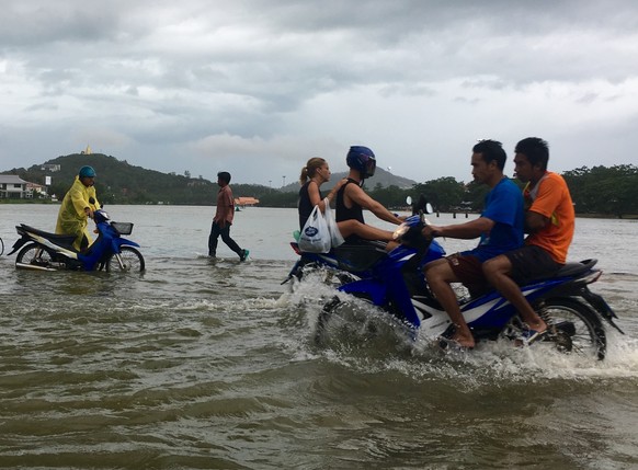 Riders use a road flooded by an overflowing lake on Ko Samui, Thailand Thursday, Jan. 5, 2017. Heavy rains battering parts of Thailand are causing localized flooding on the resort island during a peak ...
