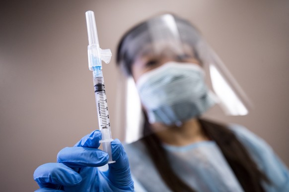 epa08746323 A nurse holds a syringe containing flu vaccine at a free mobile clinic in Lakewood, California, USA, 14 October 2020. Flu vaccine manufacturers have increased production in anticipation of ...