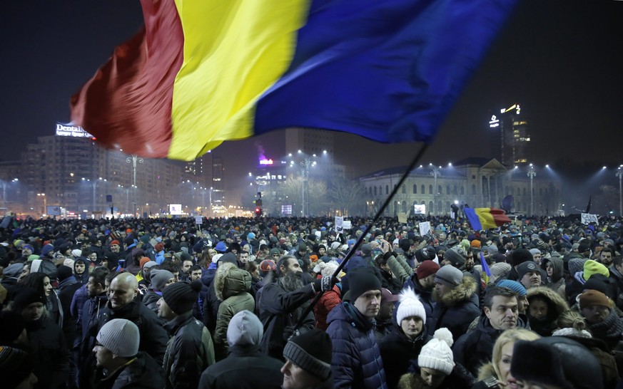 epaselect epa05763814 A Romanian man waves large-scale of the national flag as people shout anti-government slogans during a protest rally in front of government headquarters in downtown Bucharest, Ro ...