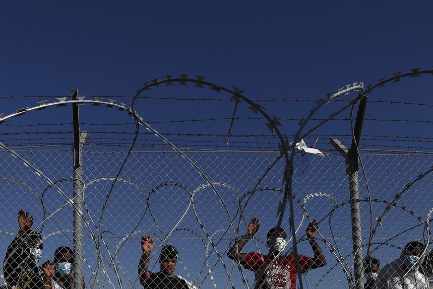 FILE - Migrants stand behind a fence inside a refugee camp in Kokkinotrimithia outside of capital Nicosia, Cyprus, Friday, Feb. 5, 2021. The United Nations refugee agency said Friday, Aug. 11, 2023, i ...