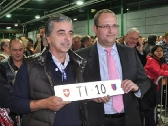 Käufer Francesco Magistra (l.) nimmt sein eben ersteigertes Schild TI 10 vom Tessiner Staatsrat Norman Gobbi entgegen.