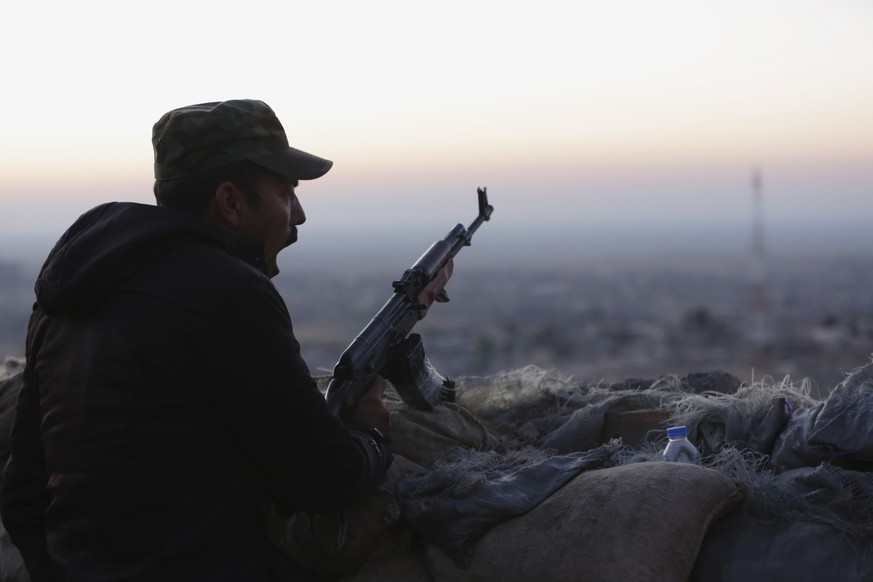 FILE - In this Friday, Nov. 13, 2015, file photo a Kurdish fighter, known as a peshmerga, yawns as he stands guard on the frontline in Sinjar, Iraq. A series of political spats that erupted in Baghdad ...