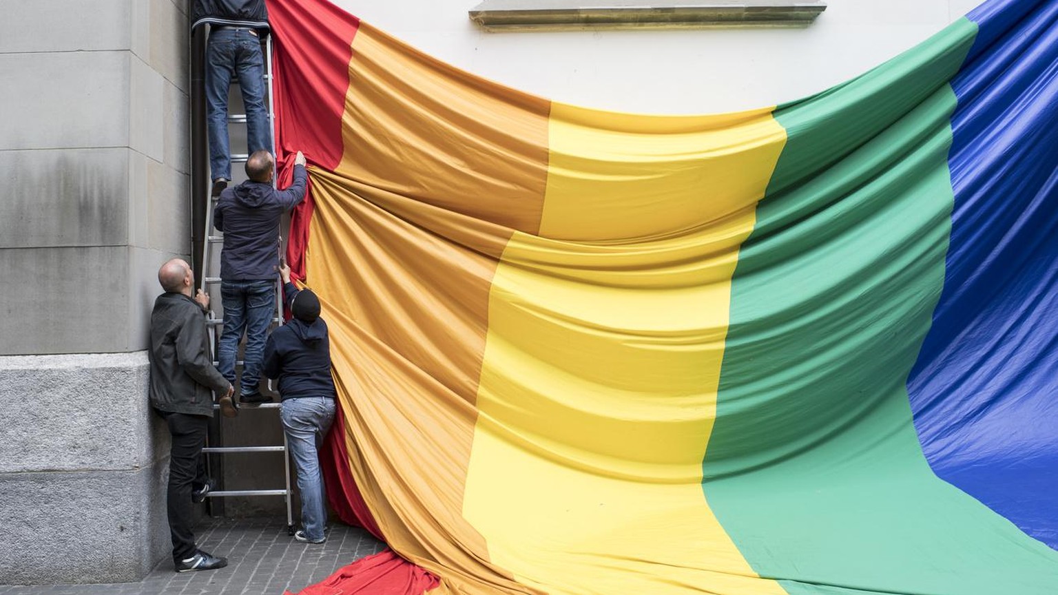 Swiss LGBT activists prepare a flag during a vigil for those killed and wounded in the Sunday June 12, mass shooting at a gay nightclub in Orlando, at a church in Zuerich, Switzerland, Monday, June 13 ...