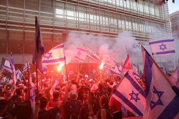 epa10752495 Anti government demonstrators light flares during a protest against justice system reform in the stock market building in Tel Aviv, Israel, 18 July 2023. Mass protests continue across the  ...