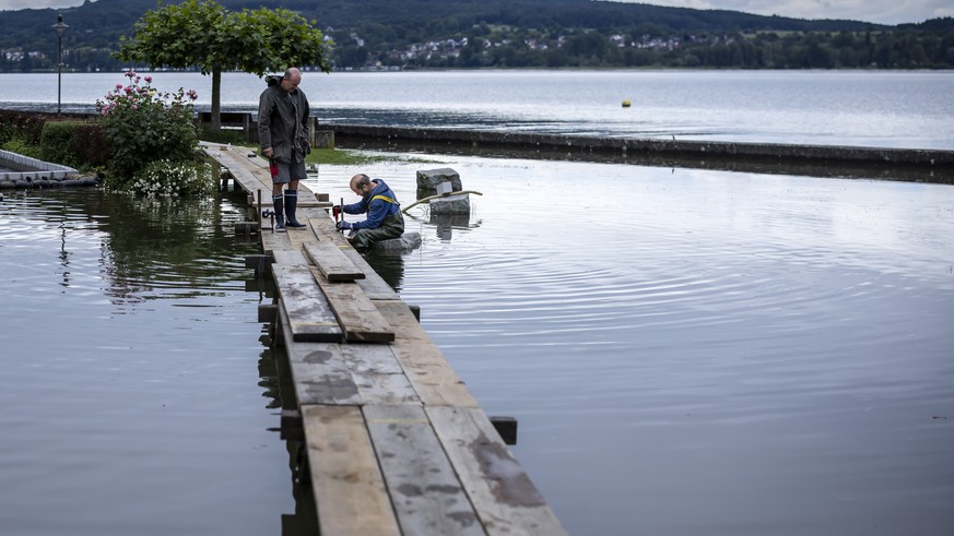 A municipal employee and and a volunteer build footbridges as the Lake Untersee, the western part of Lake Bodensee overflows its banks, in Berlingen, Switzerland, Tuesday, June 11, 2024. On Tuesday, t ...