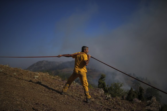 A firefighter carries a hosepipe as they extinguish a wildfire in Koycegiz, Mugla, Turkey, Monday, Aug. 9, 2021. Wildfires in Turkey, described as Turkey&#039;s worst in living memory, started on July ...