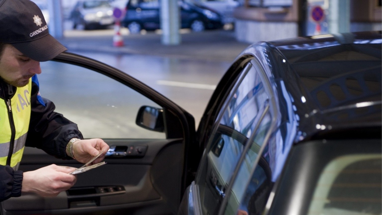 A frontier guard checks the driver of a car at the customs facilities in Basel at the border of Switzerland and Germany, Friday, December 12, 2008. Since midnight Switzerland is part of the Schengen z ...