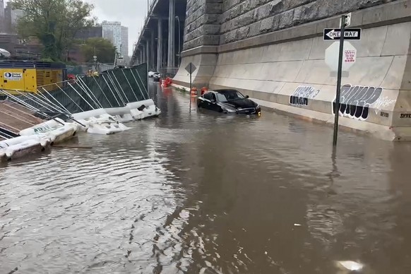 In this image taken from video, a car sits stranded in flood waters at the base of the Williamsburg Bridge, Friday, Sept. 29, 2023, in New York. A potent rush-hour rainstorm has swamped the New York m ...