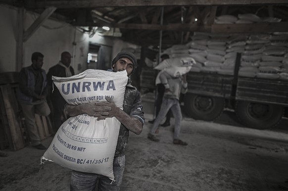 epa06988519 (FILE) A Palestinian refugee carries a sack with flour at the United Nation food distribution center in al Shateaa refugee camp in the northern Gaza city, 15 January 2018 (reissued 31 Augu ...