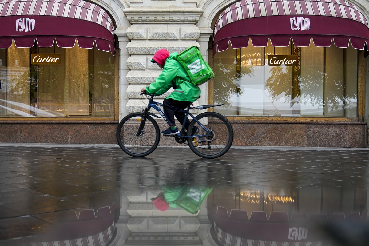 A food delivery man rides a bicycle along the GUM department store with a Cartier boutique closed due to sanctions in Moscow, Russia, Tuesday, May 31, 2022. As Russia's military operation in Ukra ...