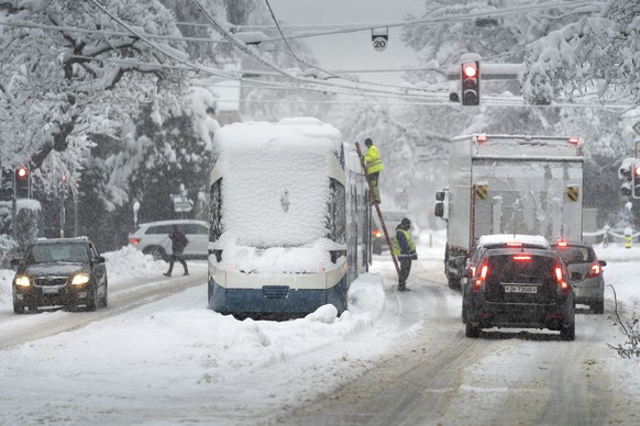Mitarbeiter der Verkehrsbetriebe Zuerich VBZ versuchen ein im Schnee liegendes Tram zu reparieren, in Zuerich am Freitag, 15. Januar 2021. Nach den anhaltenden Schneefaellen in der oestlichen Schweiz ...