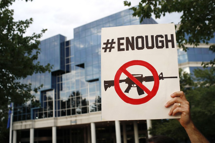 FILE - A protester holds a sign outside the National Rifle Association&#039;s headquarters building during a vigil for recent victims of gun violence on Aug. 5, 2019, in Fairfax, Va. A ransomware gang ...