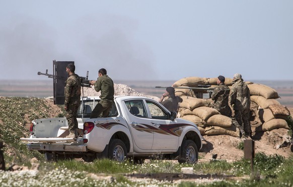 Kurdish People&#039;s Protection Units (YPG) fighters and foreign fighters (R) who joined the YPG, man their weapons during what the YPG said was an offensive against them by Islamic State fighters, i ...